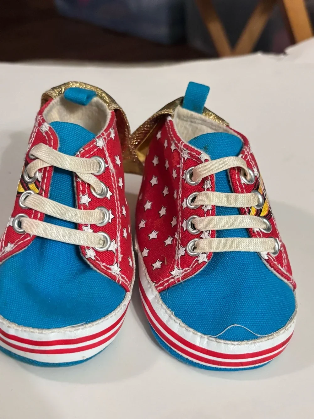 DC Comics baby sneaker with Wonder Woman logo. Red canvas with Gold Capes.
